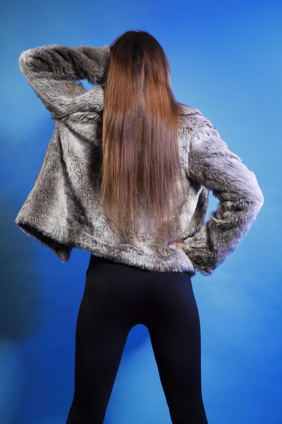 young woman in fur long hair blue background - Foto, imagen