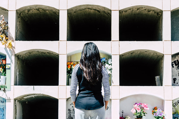 Donna da dietro contemplando la tomba di una persona cara
 - Foto, immagini