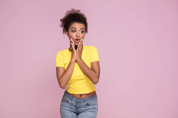 Excited african american woman looking at camera, posing on pink pastel background. - 写真・画像