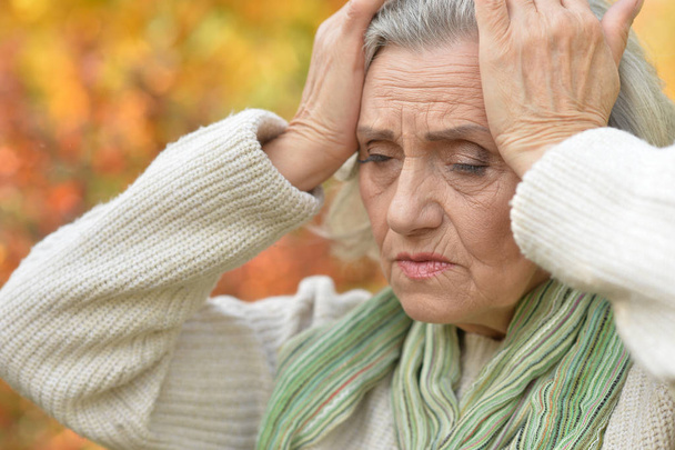Portrait of sad senior woman with headache in  park - Foto, afbeelding