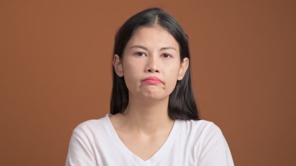 disappointed asian woman on brown background - Video, Çekim