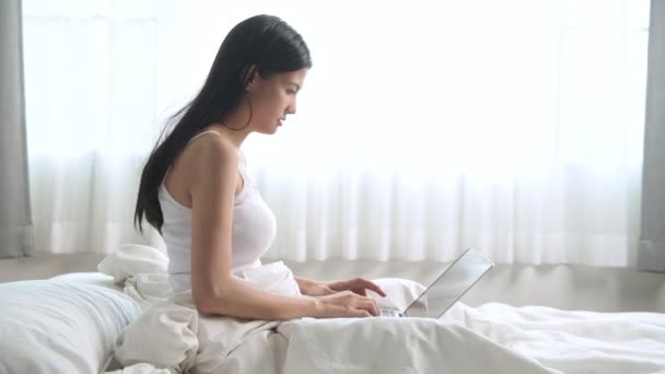 asian woman using laptop and then becoming surprised and excited - Materiał filmowy, wideo