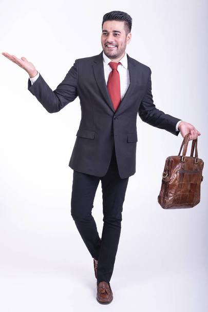 Businessman isolated in white background. Handsome young indian businessman in suit with bag portrait, confident smile looks. Full length shot. - Φωτογραφία, εικόνα