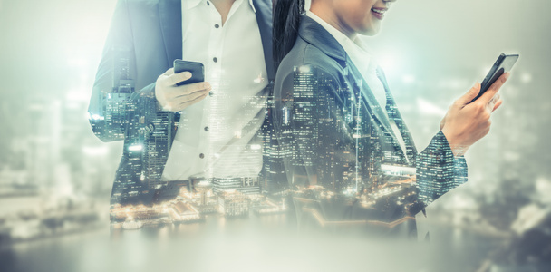 Young business people using mobile phone with modern city buildings background. Future telecommunication technology and internet of things ( IOT ) concept. - Photo, Image