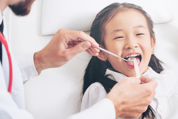 Mutlu çocuk diş diş kliniği içinde inceleyerek dostu genç diş hekimi. Diş Hekimliği kavramı. - Fotoğraf, Görsel