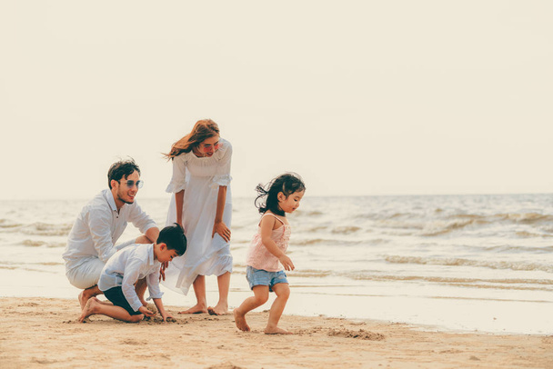 Heureuse famille de père, mère et enfants va vacances sur une plage de sable tropical en été
. - Photo, image