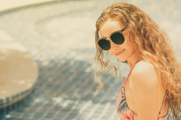 高級リゾートのスイミング プールで楽しい時間を持っている水着を着て幸せな若い女。夏旅行休暇の概念. - 写真・画像