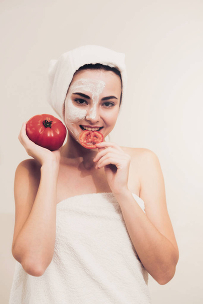 Beautiful woman having a facial mask treatment with tomato cream extract showing benefit of nature treatment. Anti-aging cosmetology, facial skin care and luxury lifestyle concept. - Foto, afbeelding