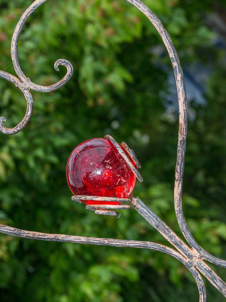 Heart-shaped garden plug decorated with a red glass ball - Photo, Image