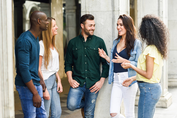 Grupo multiétnico de jóvenes que se divierten juntos al aire libre en un entorno urbano. grupo de mujeres y hombres hermosos riendo juntos
 - Foto, imagen
