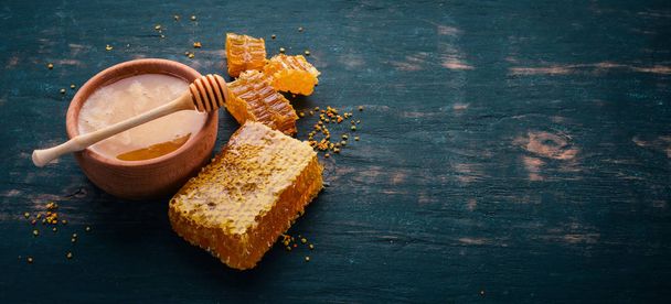 Honey in a jar and a honeycomb. On a black wooden background. Free space for text. Top view. - Foto, imagen