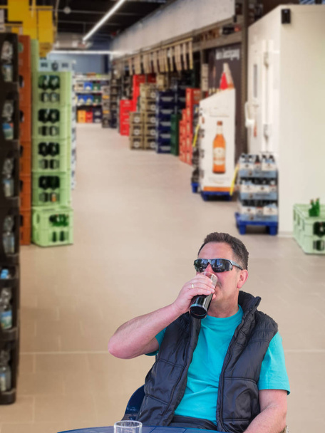 Ritratto di un uomo nel negozio di bevande con il bicchiere in mano mentre assaggia il vino. Sfocatura prevista sullo sfondo
. - Foto, immagini