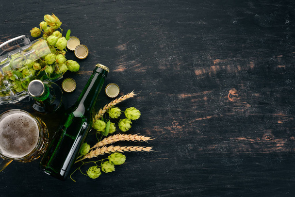 Beer and fresh hops on a black wooden background. Free space for text. Top view. - Foto, Bild