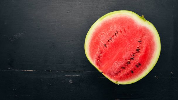 Fresh watermelon Fruits. Melon. On a black wooden background. Free space for text. Top view. - Foto, imagen