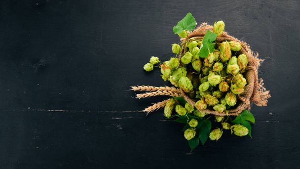 Hops and wheat in a linen bag. On an old wooden table. Free space for text. Top view. - Valokuva, kuva