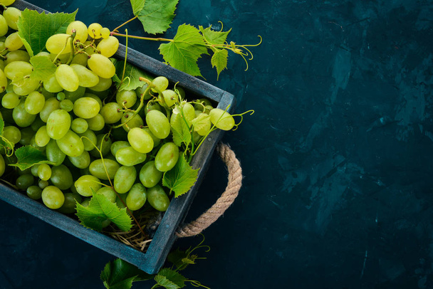 Grapes in a wooden box. Leaves of grapes. Top view. On a black background. Free space for text. - Fotó, kép