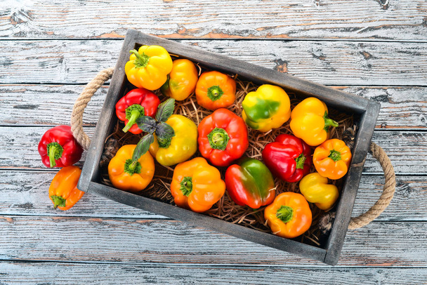 Colored Paprika in a wooden box. Top view. On a white wooden background. Free space for text. - Foto, Imagen
