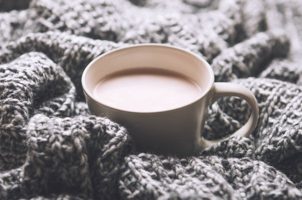 Una taza de cacao caliente con leche sobre lana gris tejida a cuadros. Comodidad en casa. Vista superior
 - Foto, imagen