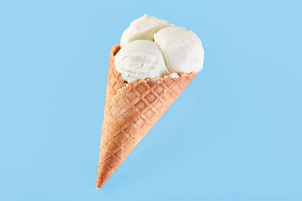 μπάλες παγωτό σε μια φλυαρώ κώνου σε μπλε φόντο. Παγωτό βανίλια σε μια φλυαρώ κώνου. - Φωτογραφία, εικόνα