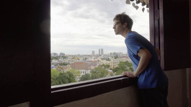 Молодой человек смотрит в окно
 - Фото, изображение