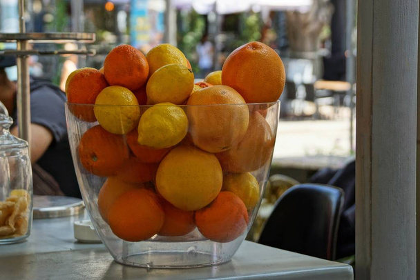 un grande vaso di vetro pieno di limoni e un'arancia sul tavolo del ristorante
 - Foto, immagini