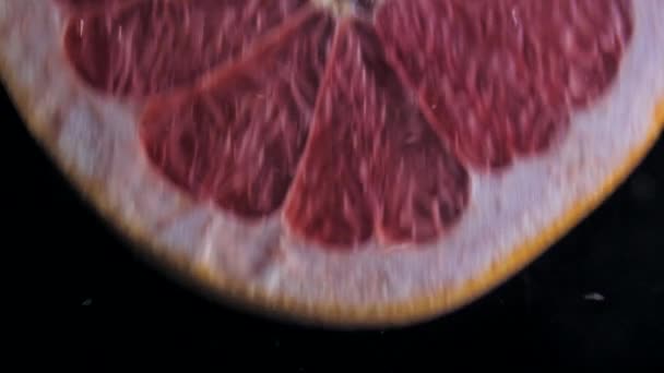Kulatý čerstvý šťavnatý grapefruit plátek do průzračnou vodou s výbušnými ohromující šplouchnutím. Podvodní vysokorychlostní zpomalený záběr na černém pozadí. Pomelo, samostatný. - Záběry, video