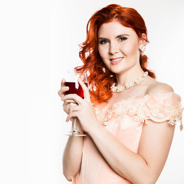 Young redhead woman drinks a red wine with a happy face and smiling with a confident smile. white background. free space for your text - Фото, зображення