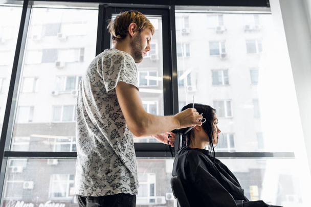 Une femme dans un salon de coiffure attendant de voir les résultats dans un miroir, souriant et parlant avec l'artiste
 - Photo, image