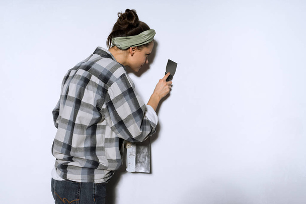 girl in a plaid shirt doing repairs in her new apartment, leveling the walls - 写真・画像