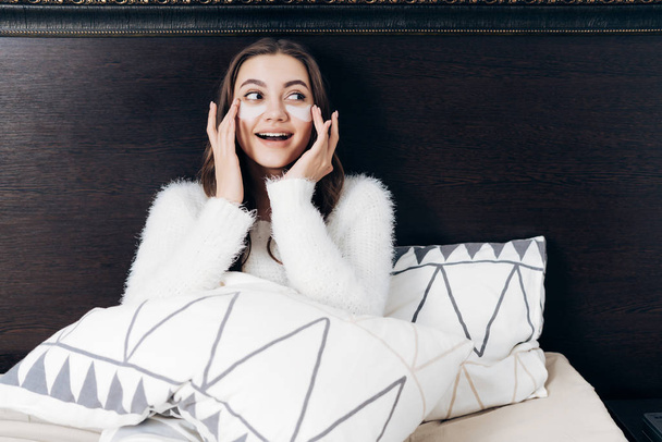 очаровательная девушка лежит в постели под одеялом, под глазами белые пятна от отеков и синяков
 - Фото, изображение