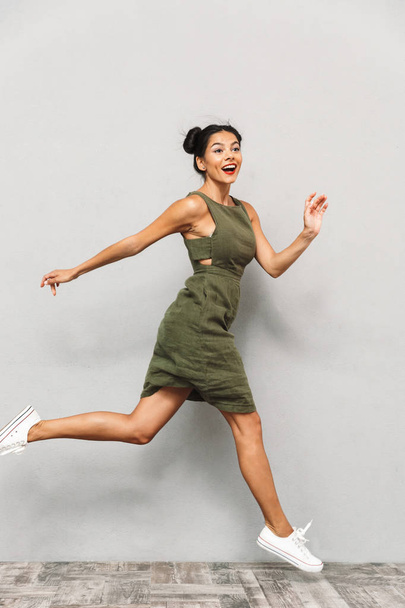 Portrait of a happy young woman in dress isolated, jumping, looking at camera - Foto, immagini