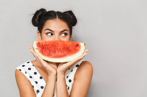 Portrait of a lovely young woman in summer dress isolated, holding watermelon slice - Foto, Bild