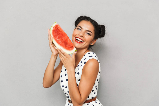 Portrait of a cheerful young woman in summer dress isolated, holding watermelon slice - Foto, Imagem
