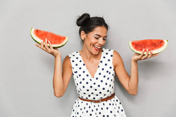 Portrait of a happy young woman in summer dress isolated, holding two watermelon slices - Foto, Imagem