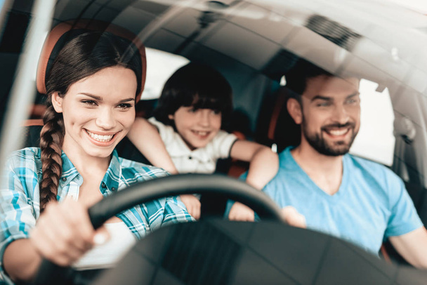 A Woman Is Sitting At The Wheel Of A New Vehicle. Smiling Family. Car Buying In A Showroom. Automobile Salon. Cheerful Driver. Happy Together. Successful Buying. Good Mood. Great Trade. - Fotografie, Obrázek