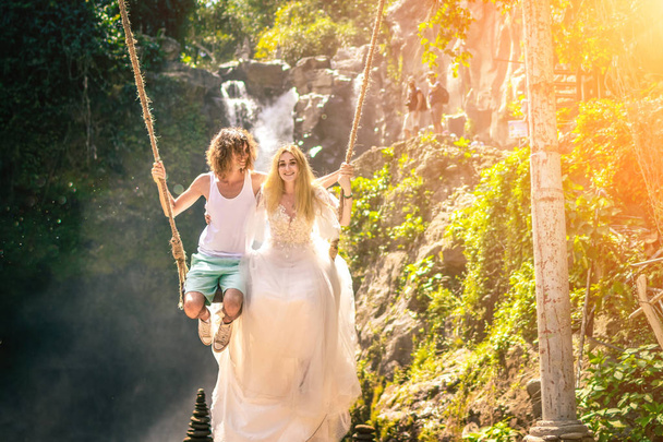 Young honeymoon couple swings in the jungle near the lake, Bali island, Indonesia. - Fotografie, Obrázek