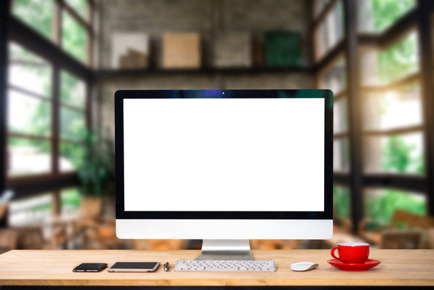 Area di lavoro con monitor per computer, tastiera, tazzina da caffè con schermo bianco su un tavolo in interni luminosi per uffici
. - Foto, immagini