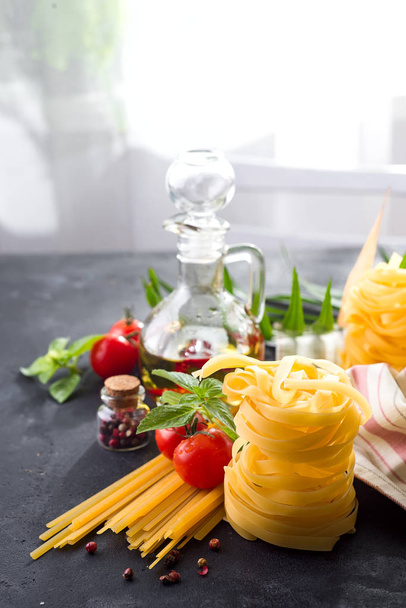 Italialaista pastaa tomaattien, mausteiden ja öljyn kanssa tummalla kivipöydällä. Vapaa tila tekstille. Yläkuva
 - Valokuva, kuva