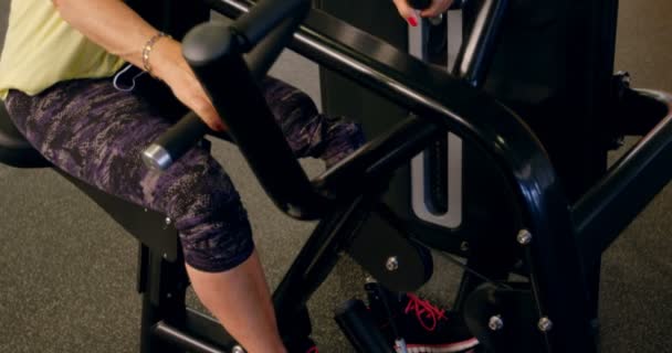 Senior woman doing back exercise on machine in fitness studio 4k - Filmmaterial, Video
