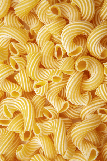 ellow background of pasta in the form of tubes spun in a spiral - Foto, Imagen