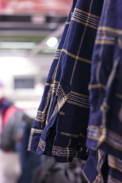 Camisas xadrez azuis masculinas em cabides na loja
 - Foto, Imagem