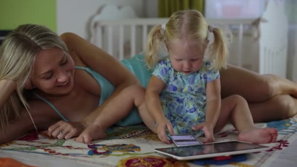 Donna con smartphone e bambino con tablet a casa. Famiglia con gadget
. - Filmati, video
