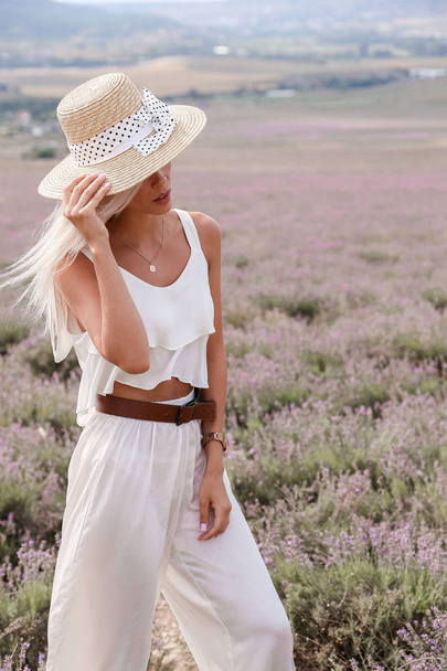 fashion outdoor photo of beautiful sensual girl with blond hair in elegant white dress and straw accessories posing in provence lavender field - Fotografie, Obrázek