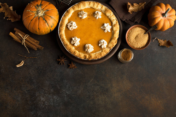 Pumpkin Pie with whipped cream and cinnamon on rustic background, top view. Homemade pastry for Thanksgiving traditional Pumpkin Pie. - Foto, afbeelding