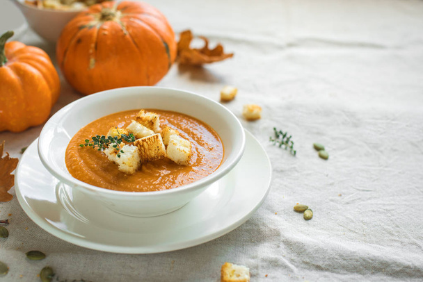 Pumpkin soup and organic pumpkins, top view. Seasonal autumn food - Spicy pumpkin soup with croutons. - Фото, изображение