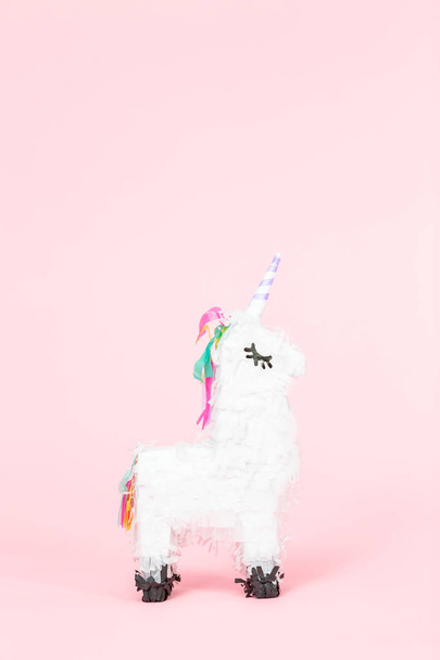 White unicorn pinata on a pink background. - Фото, изображение