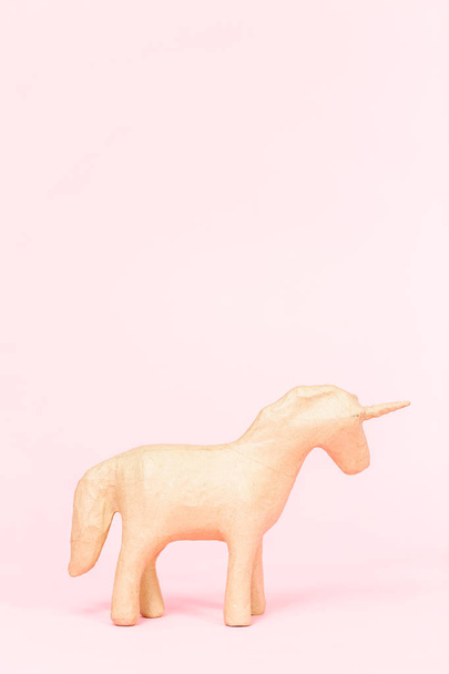 Figura mache de papel inacabado de unicornio sobre fondo rosa
. - Foto, Imagen