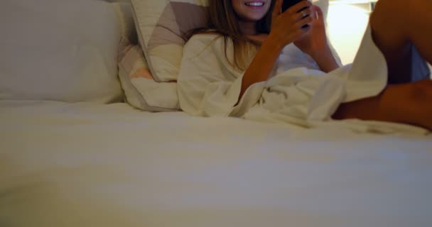 Усміхнена жінка використовує мобільний на ліжку в спальні вдома 4k
 - Кадри, відео