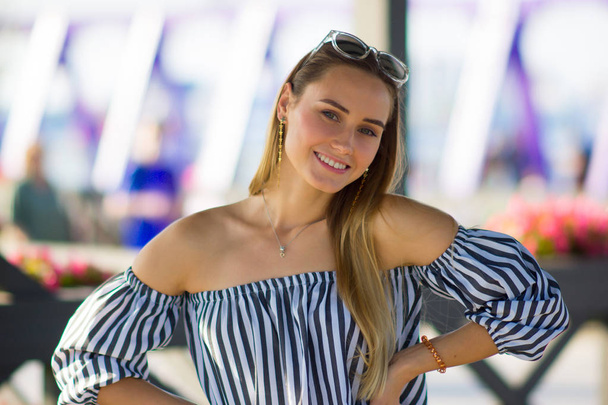 Portrait of a young woman on a bright background. Happy girl smiling and enjoying a summer walk - Фото, изображение