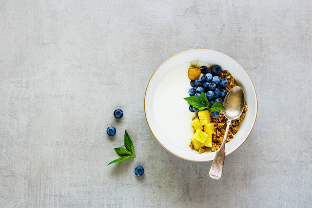 Healthy breakfast bowl. Flat-lay of granola, greek yogurt, fresh fruit and berries on light table background. Clean eating, vegetarian, diet food concept. Top view - Fotó, kép